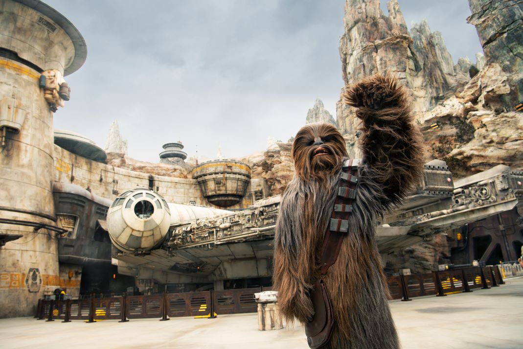 Wookie waving in front of the spaceship the Millenium Falcon