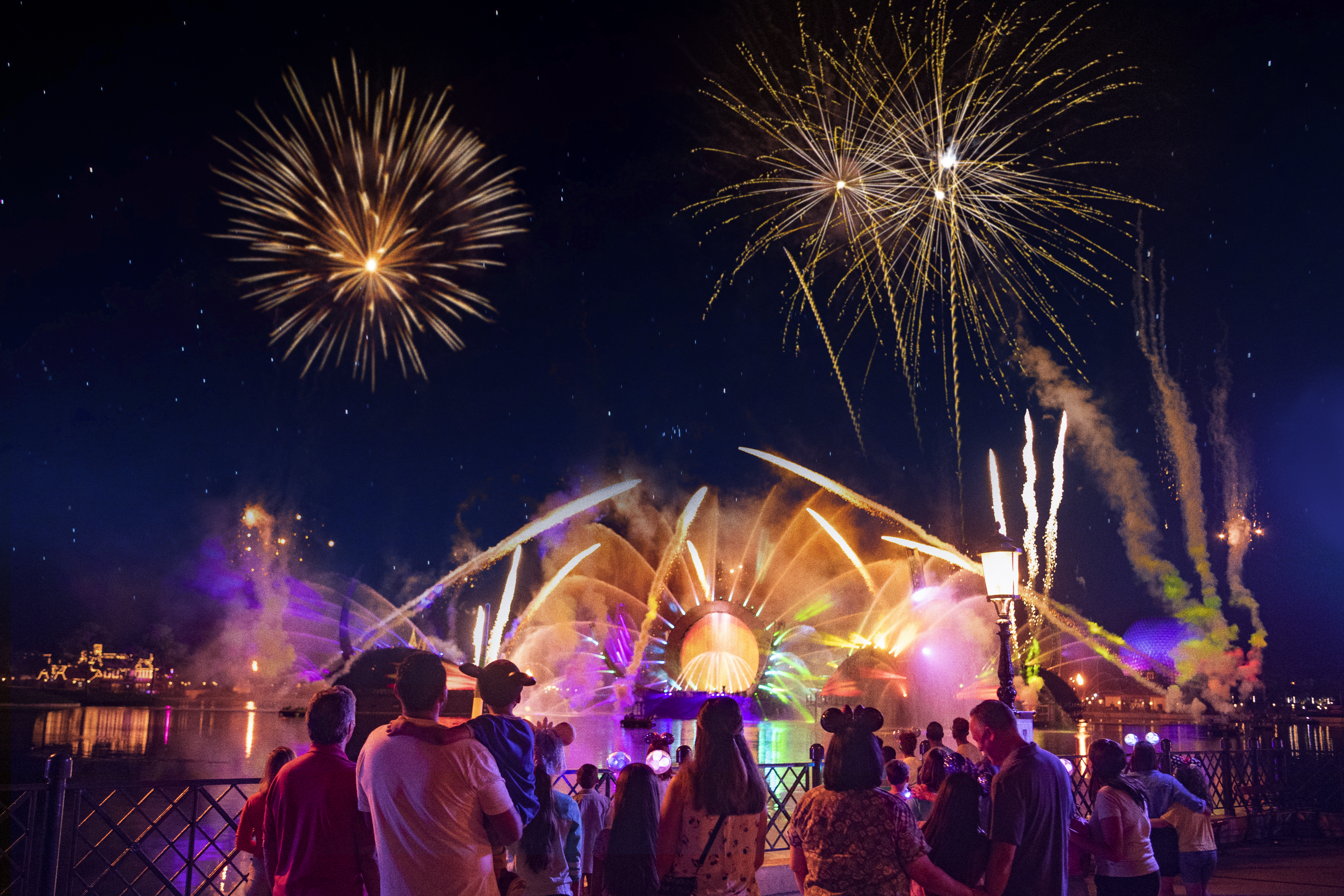 Bright fireworks and pyrotechnics light up the night sky as a crowd watches